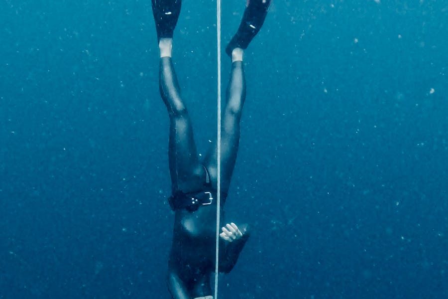 Freediver descending into deep blue ocean