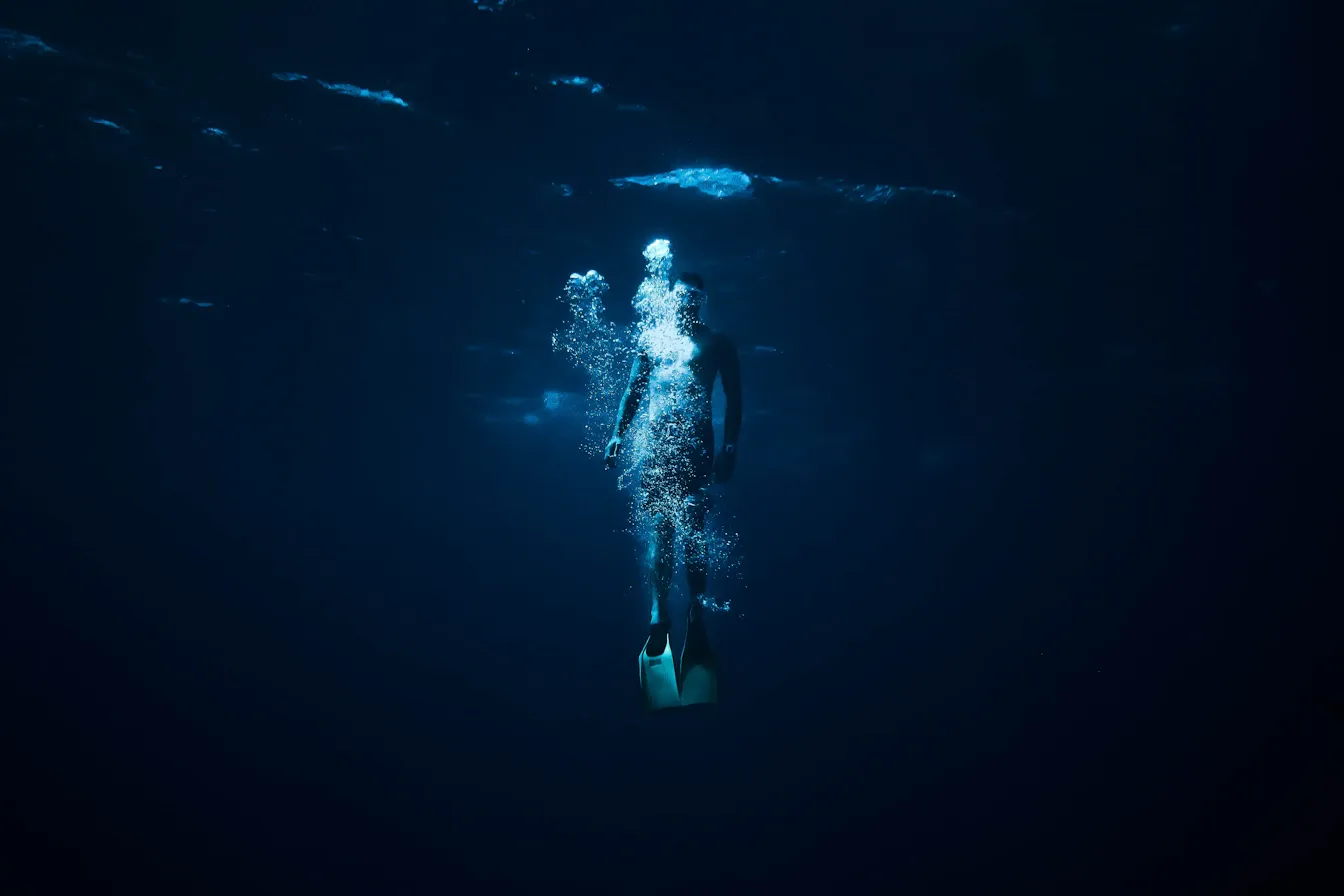 Freediver vanishing into the black abyss on a single breath