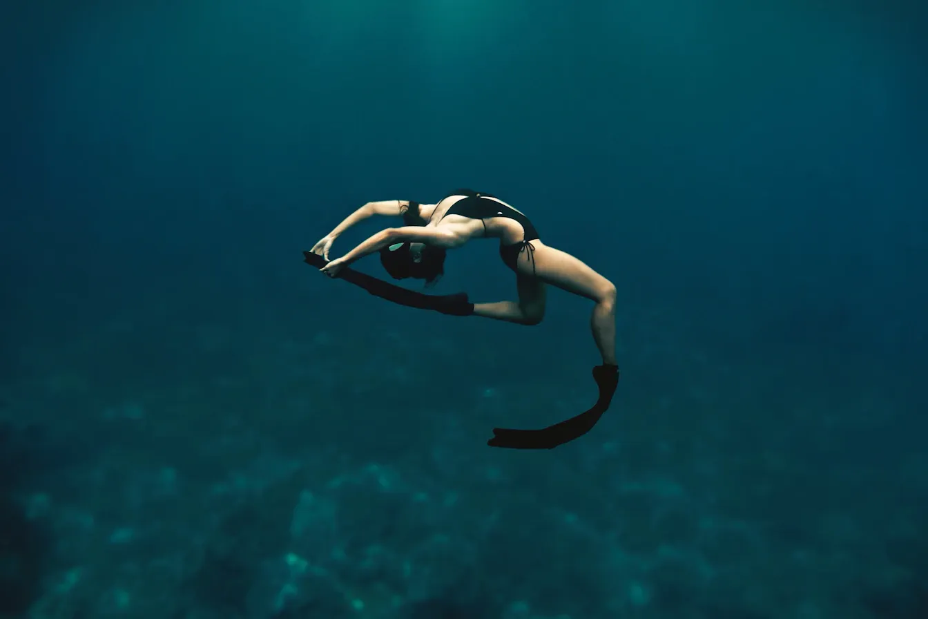 Freediver arching gracefully in mid-water, body adapted to the deep