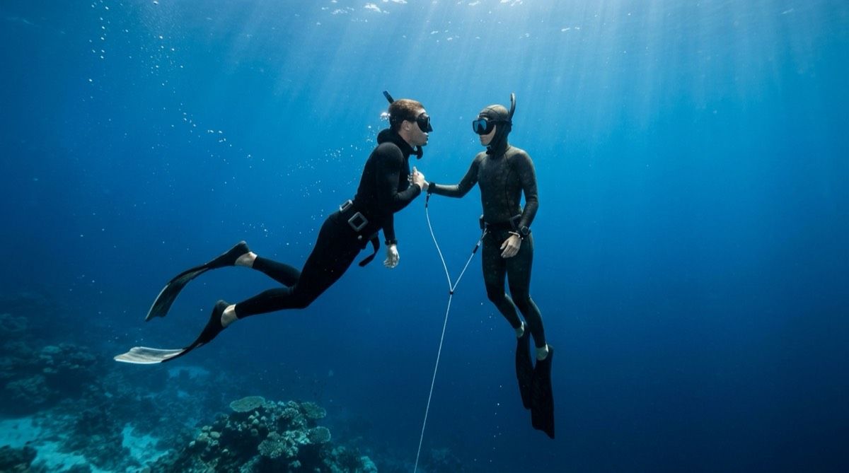 Safety freediver escorting a buddy on ascent along the line