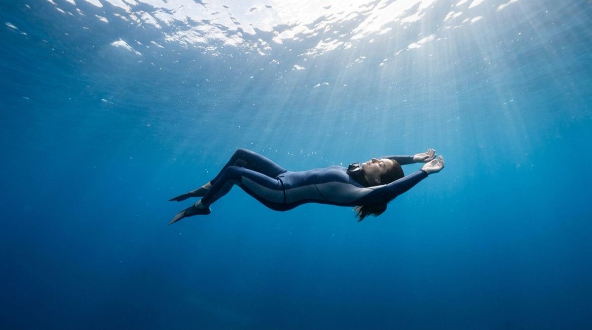 Freediver relaxing underwater in calm blue water